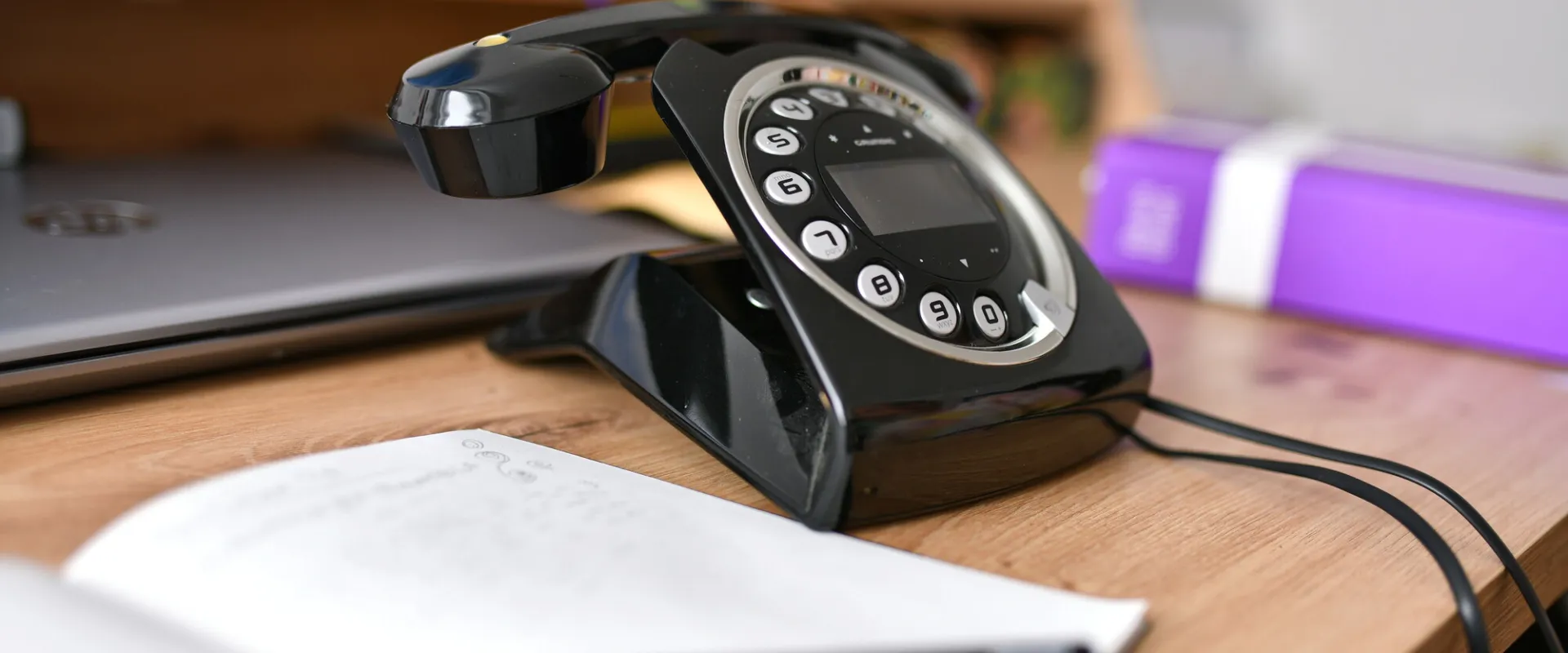 Telefon und Notizbuch am Schreibtisch