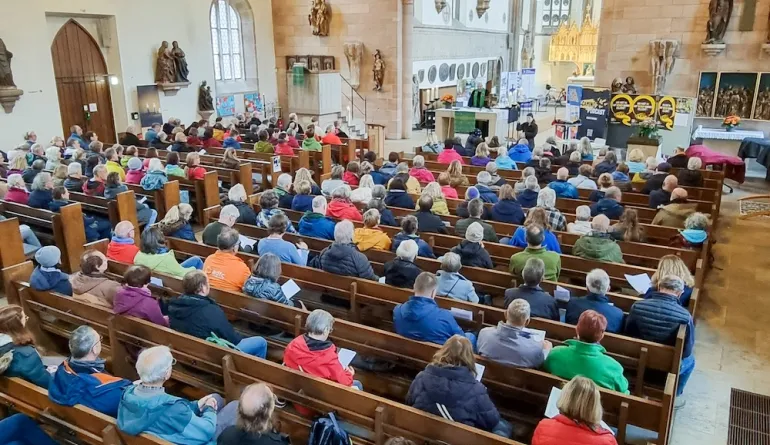 Blick von hinten in den Gottesdienstraum, eine volle St. Jakobskirche, die Stuhlreihen sind alle belegt