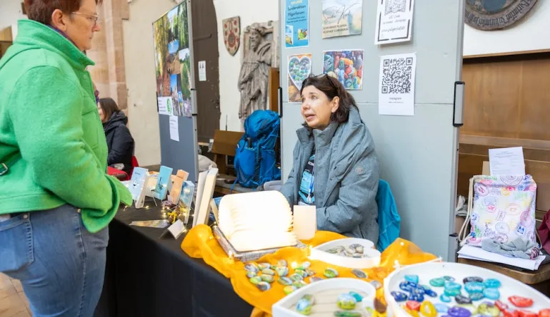 Frau sitzt am Informationsstand und unterhält sich mit Besucherin