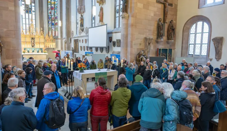 Besucher:innen stehen um den Altar zum Reisesegen versammelt