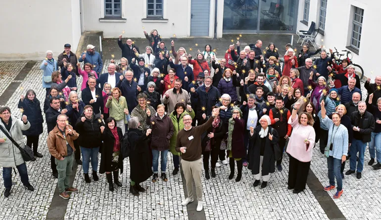 Menschen in einer Gruppe, die Wunderkerzen in der Hand halten und vor dem Gebäude stehen