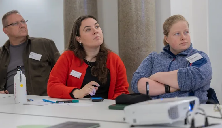 Zwei Teilnehmerinnen hören im Workshop aufmerksam zu