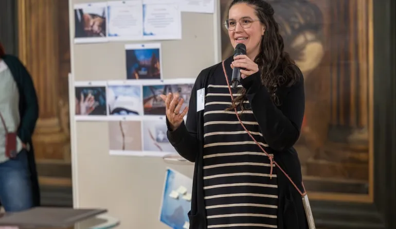 Expertin stellt ihr Projekt vor, im Hintergrund eine Stellwand mit Informationen