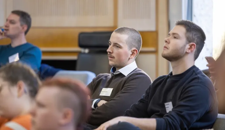 Zwei Teilnehmer hören den Ausführungen im Auditorium zu