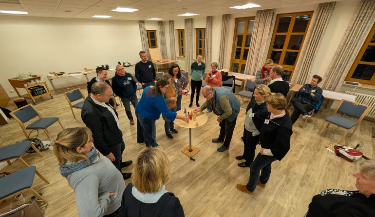 Ein Tisch in der Mitte, auf dem Holzfiguren stehen auf den die teilnehmenden gemeinsam schauen