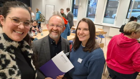 3 Referenten, lächelnd, mit der Teilnehmermappe in der Hand